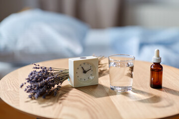 sleep disorder, bedtime and morning concept - close up of alarm clock, lavender essential oil and...