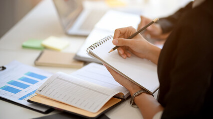 Business woman taking a notes on her notepad in the financial meeting.