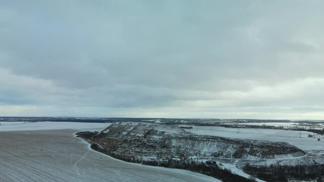 Flying over a snowy field. The city dump is visible, covered with snow. Mothballed waste landfill. Aerial photography.
