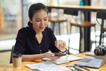 Businesswoman or college student using smartphone at her working desk.