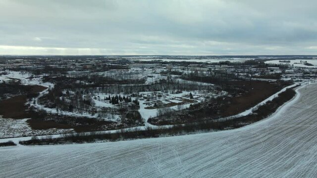 Flying over a snowy field. Straw bales are stacked. Traces of agricultural tillage are visible under the snow. Aerial photography.