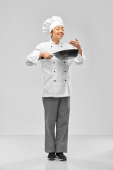 cooking, culinary and people concept - happy smiling female chef with frying pan smelling food over grey background