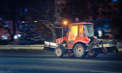 Tractor with snow plow and rear brush for cleaning sidewalks, walkways and roads moving on city at...