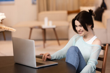 woman smiling while online with computer at home, student freelancer happy about success in business in home office