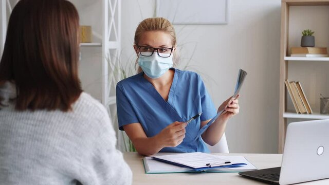 Lungs x-ray. Female doctor. Medical consultation. Qualified woman studying fluorography photo of patient in light room interior.