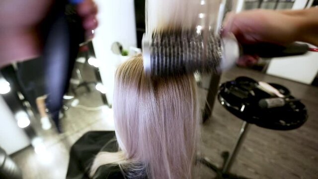 Drying long blonde hair with hair dryer and round brush