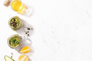 Detox green smoothie - avocado, microgreen, lemon and honey on a white stone or concrete background. Harsh lighting and shade.
