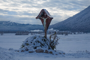 Chapel, crucifix on a snowy Planina field, Slovenia