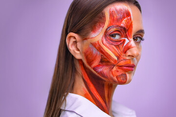 Cosmetology concept. Young woman with half of face with muscles structure under skin. Model for medical training on a light background. Close up photo of face human anantomy.
