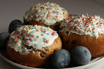 Breakfast for Easter, on the table in the light of the sun there is a plate with Easter cakes and painted eggs, in the background a vase with willow.