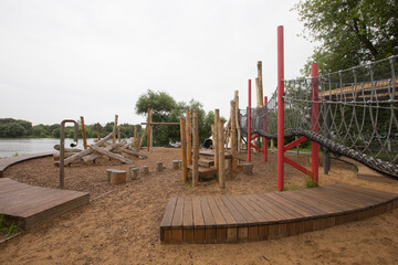 Fototapeta na wymiar children's playground made of environment, eco-friendly materials. Wooden tree trunk sides, swings, net bridges, climbers. Beach number 2, Serebryany Bor (Silver Pinewood) forest park. Moscow, Russia