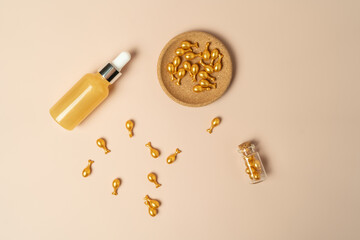 Fototapeta na wymiar A face serum or oil in golden capsules lying on a beige background