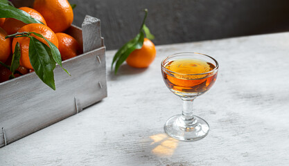 A shot with tangerine liqueur on a white wooden table © t.sableaux