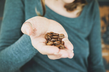 Woman hand holding natural coffee grains