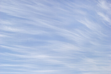 White cirrus clouds on the background blue sky.