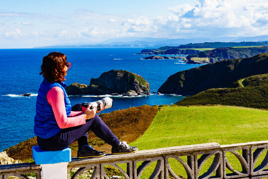 Tourist with camera on Asturias coast, Spain