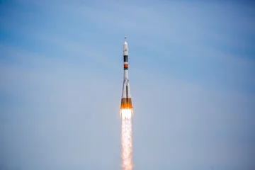 Foto op Plexiglas Take-off of a real launch vehicle from a spaceport. A rocket takes off into the sky against a background of clouds. Startup concept, power of science and technology. © Vera