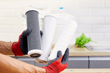 Purification of water in the kitchen with filters. Aqua filter cartridge in human hand. - obrazy, fototapety, plakaty