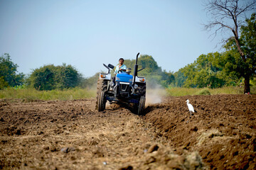 Obraz premium Indian farmer working with tractor in agriculture field.