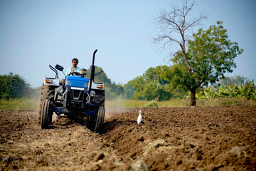 Indian farmer working with tractor in agriculture field.