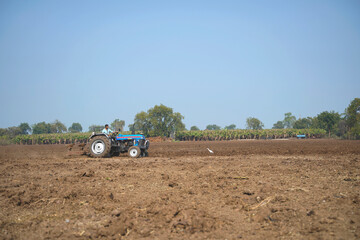 Indian farmer working with tractor in agriculture field.