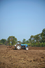 Obraz premium Indian farmer working with tractor in agriculture field.