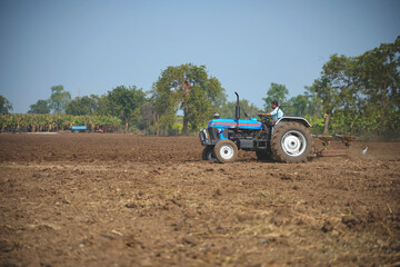 Obraz premium Indian farmer working with tractor in agriculture field.