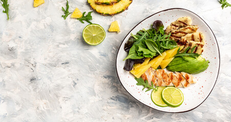 Grilled chicken breast, pineapple, green rocket salad, lime and olive oil. Healthy juicy food. banner, menu recipe place for text, top view