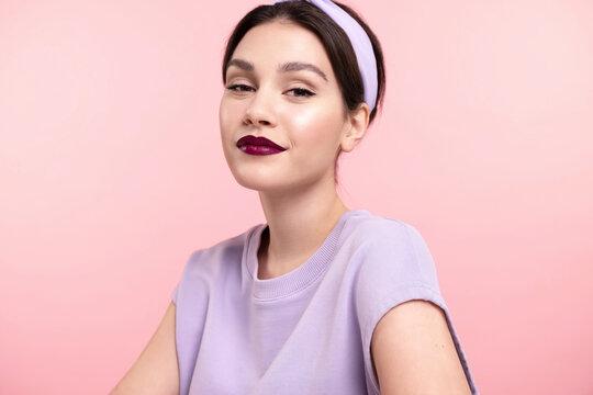 Stylish modern  pretty girl with trendy makeup, healthy glowing skin, lavender headband friendly smiling on pink studio background. Skincare and make up cosmetics advertising, beauty fashion blog