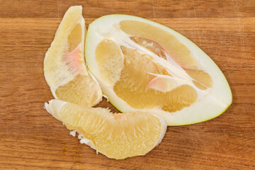 Slices of ripe pomelo on a wooden cutting board