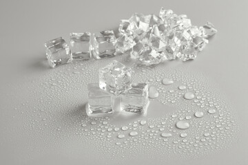 Broken ice cubes on a gray background with water droplets