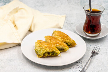 Pistachio baklava (Sobiyet) on stone background. Traditional Turkish cuisine delicacies. Close-up.