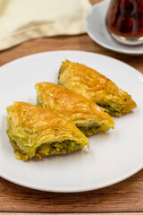 Pistachio baklava (Sobiyet) on wooden background. Traditional Turkish cuisine delicacies. Close-up.
