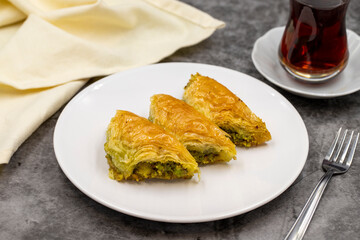 Pistachio baklava (Sobiyet) on dark background. Traditional Turkish cuisine delicacies. Close-up.