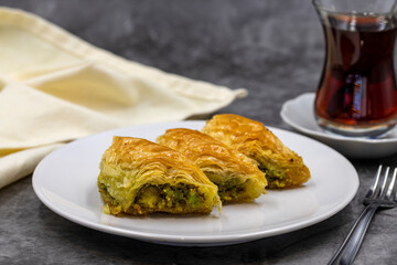 Pistachio baklava (Sobiyet) on dark background. Traditional Turkish cuisine delicacies. Close-up.