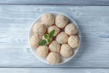 Top view of healthy raw paleo energy coconut balls in ceramic plate on wooden background.