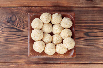 Top view of healthy raw paleo energy coconut balls in wooden plate on wooden background.