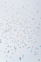 Silver star shaped confetti on light grey background. Celebration concept. Festive party invitation. Vertical photo. 