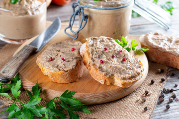 Fresh homemade chicken liver pate on bread on rustic background