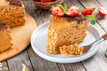 Sweet waffle cake with condensed milk, chocolate and strawberries. One piece of delicious sweet cake.