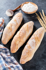 Fresh Baguette Bread on dark background. Homemade french Baguette loafs, top view.