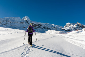 A young girl with snow rackets, walks through a completely snowy landscape in the Pyrenees mountain range (Spain).