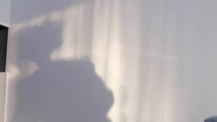 little smiling boy playing with shadows on the wall. shadow of a dancing boy reflected on the wall, carefree childhood