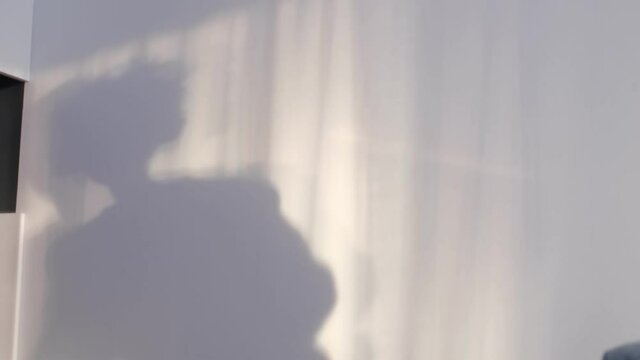 little smiling boy playing with shadows on the wall. shadow of a dancing boy reflected on the wall, carefree childhood