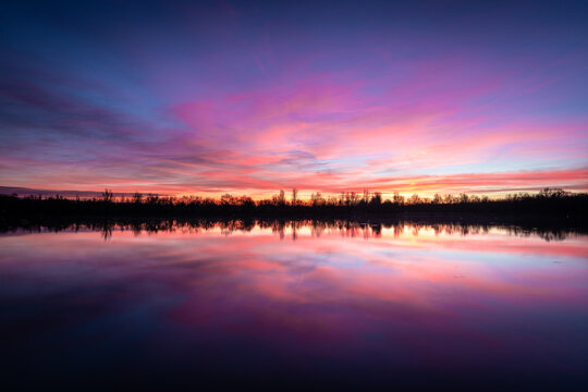 Beautiful sunset landscape sunset on the lake, reflected on the calm water - France