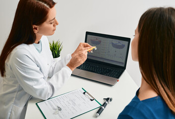 Audiologist shows a hearing aid to woman patient for treatment of deafness. Hearing clinic,...