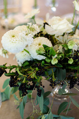 Obraz na płótnie Canvas wedding decor of white flowers and black berries on table