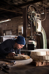 Young male carpenter working in his workshop using tools