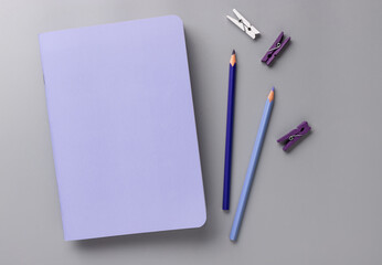 closed blank violet paper notebook with pencils on gray desk background. Color of the Year 2022 Very Peri. top view