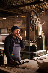 Young male carpenter smoking while taking a break in his workshop